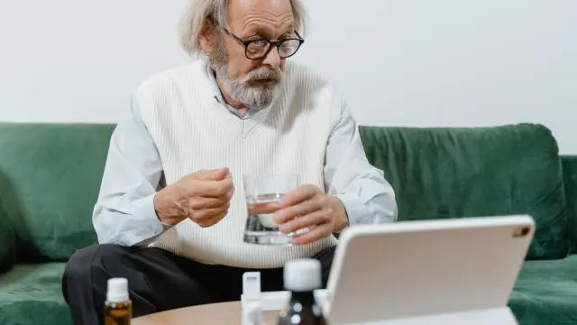 A dog owner reading a medication label at a kitchen counter with a dog resting nearby