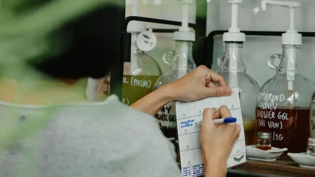 A hand turning over a dog supplement bottle to read the back label