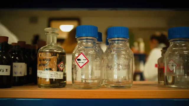 A person's hand holding a supplement bottle up to read the ingredient panel closely