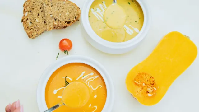 A spoonful of pumpkin puree being added to a dog's food bowl