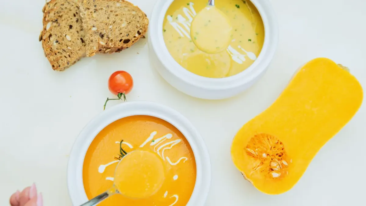 A spoonful of pumpkin puree being added to a dog's food bowl